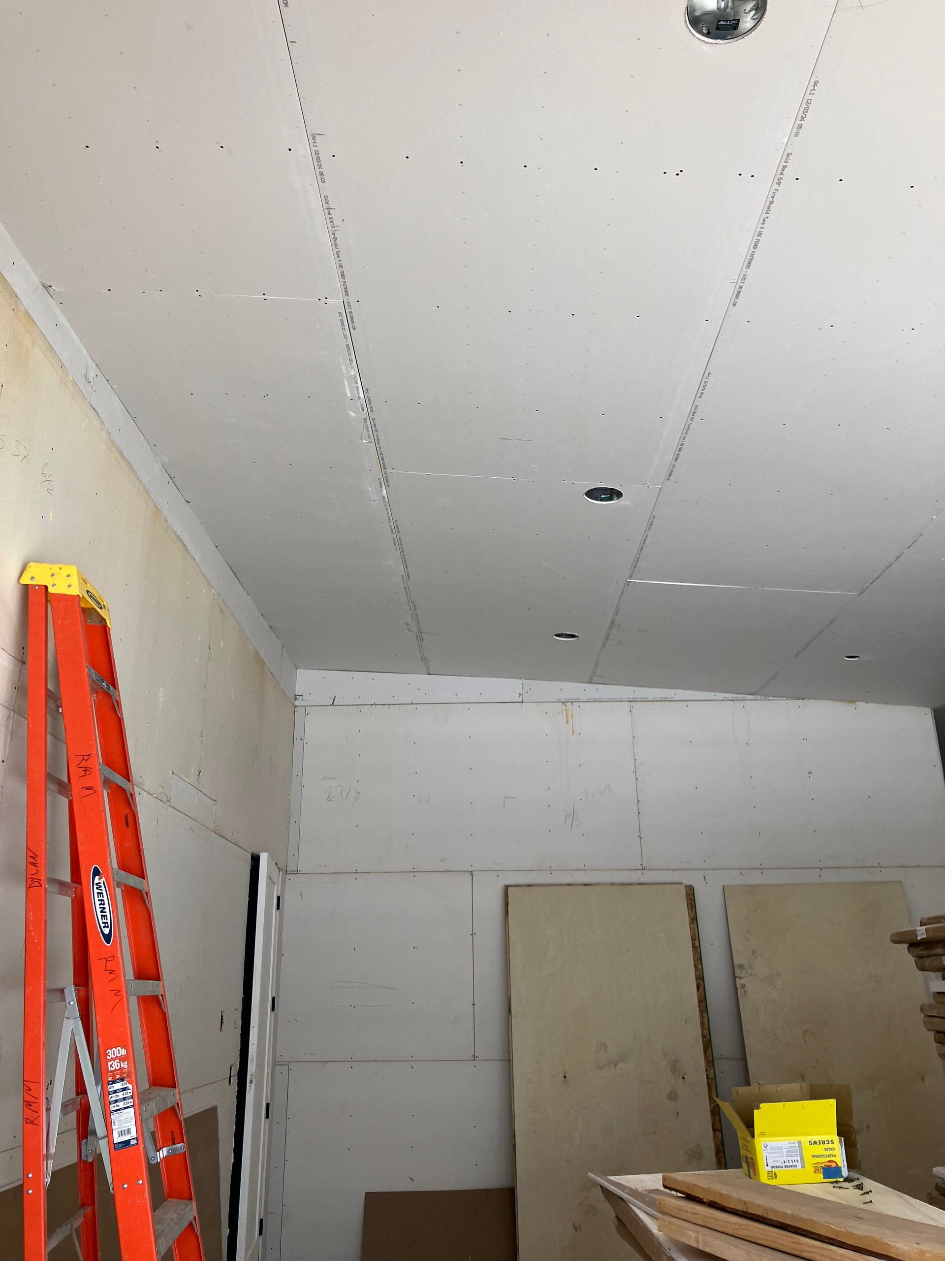 Interior construction site with ladder, drywall, and unfinished walls.