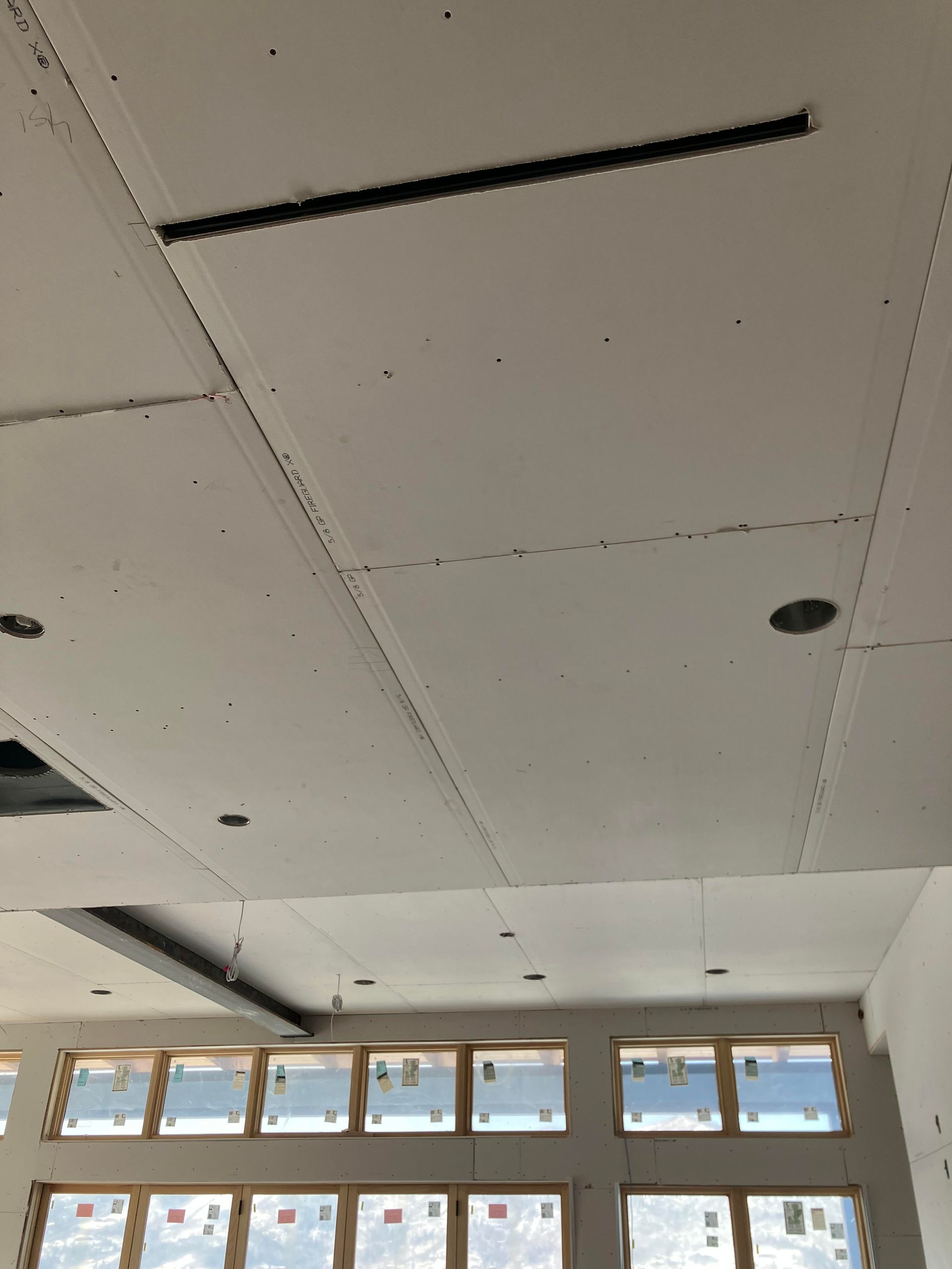 Drywall ceiling with a recessed light fixture and a long, dark linear light.