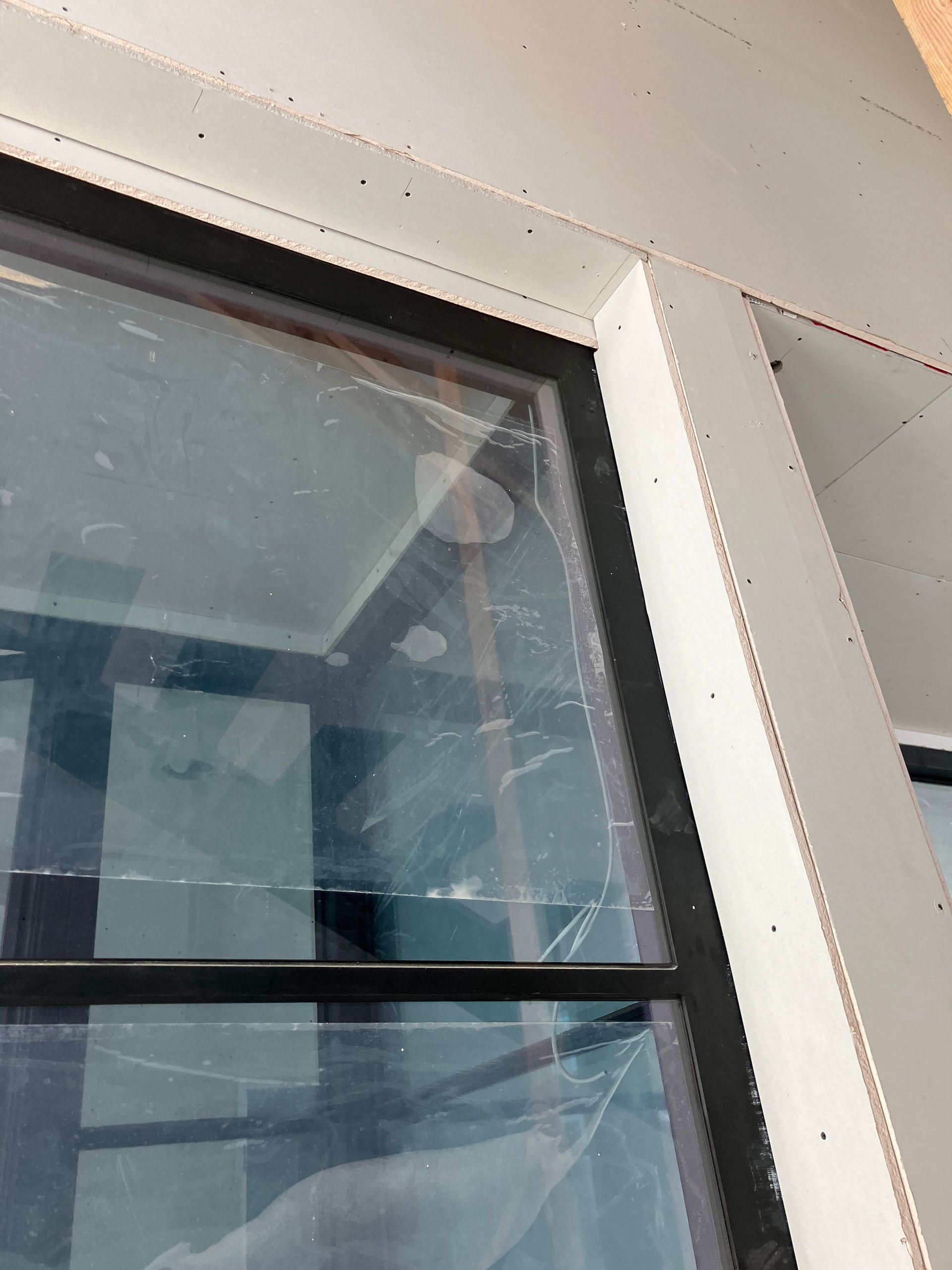 Window frame detail with glass, black trim, and gray surrounding structure.