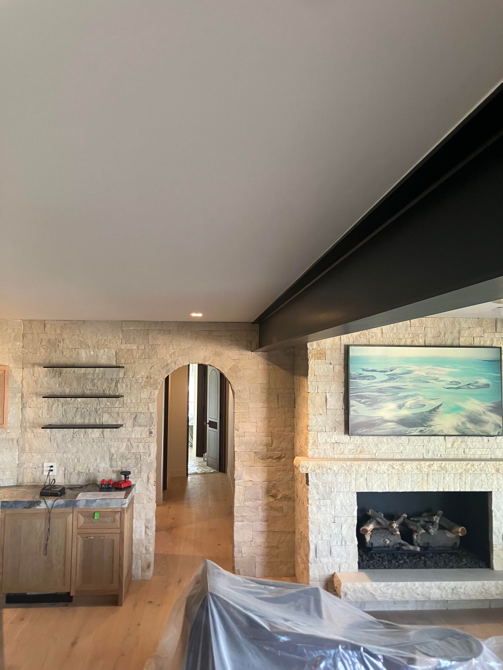 Interior with stone fireplace, doorway, built-in shelves, and exposed black beam.