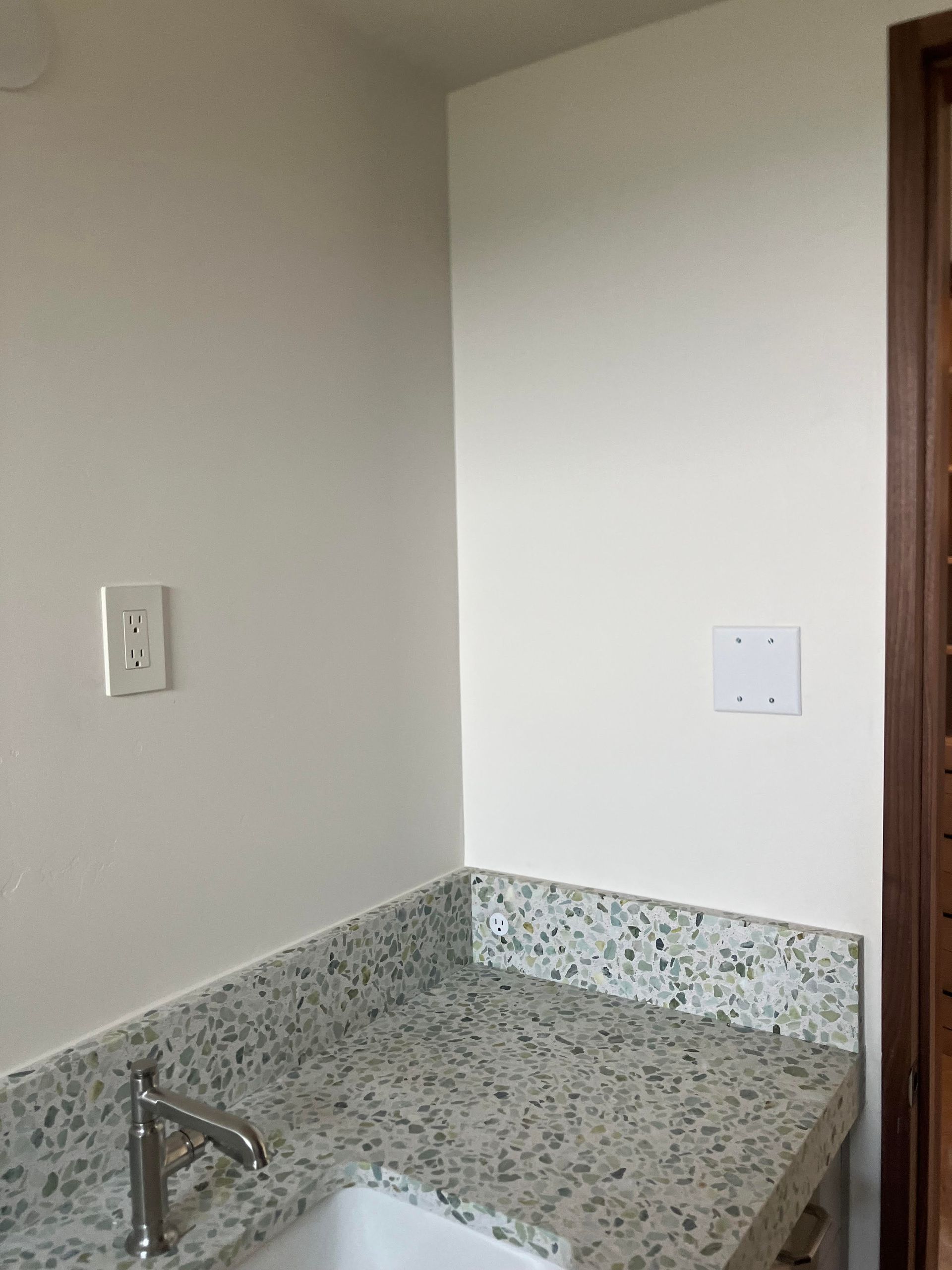 Kitchen corner with a speckled countertop, white walls, and an electrical outlet.