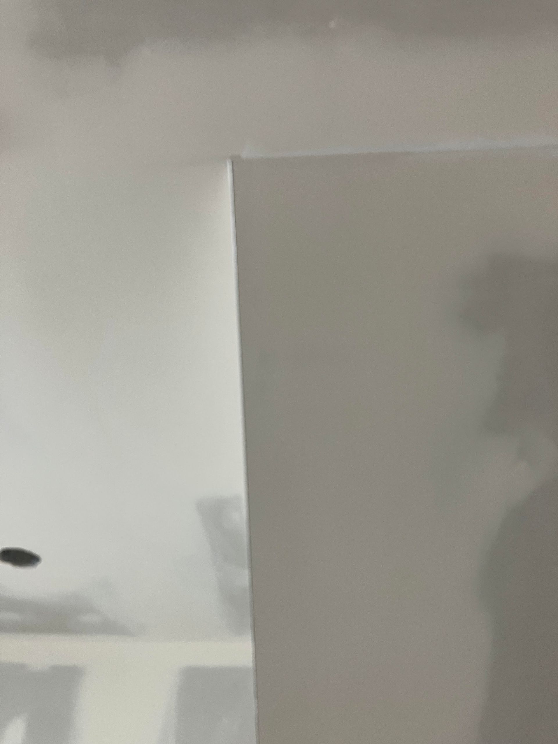 Close-up view of unfinished drywall corner in a room, with visible seam.