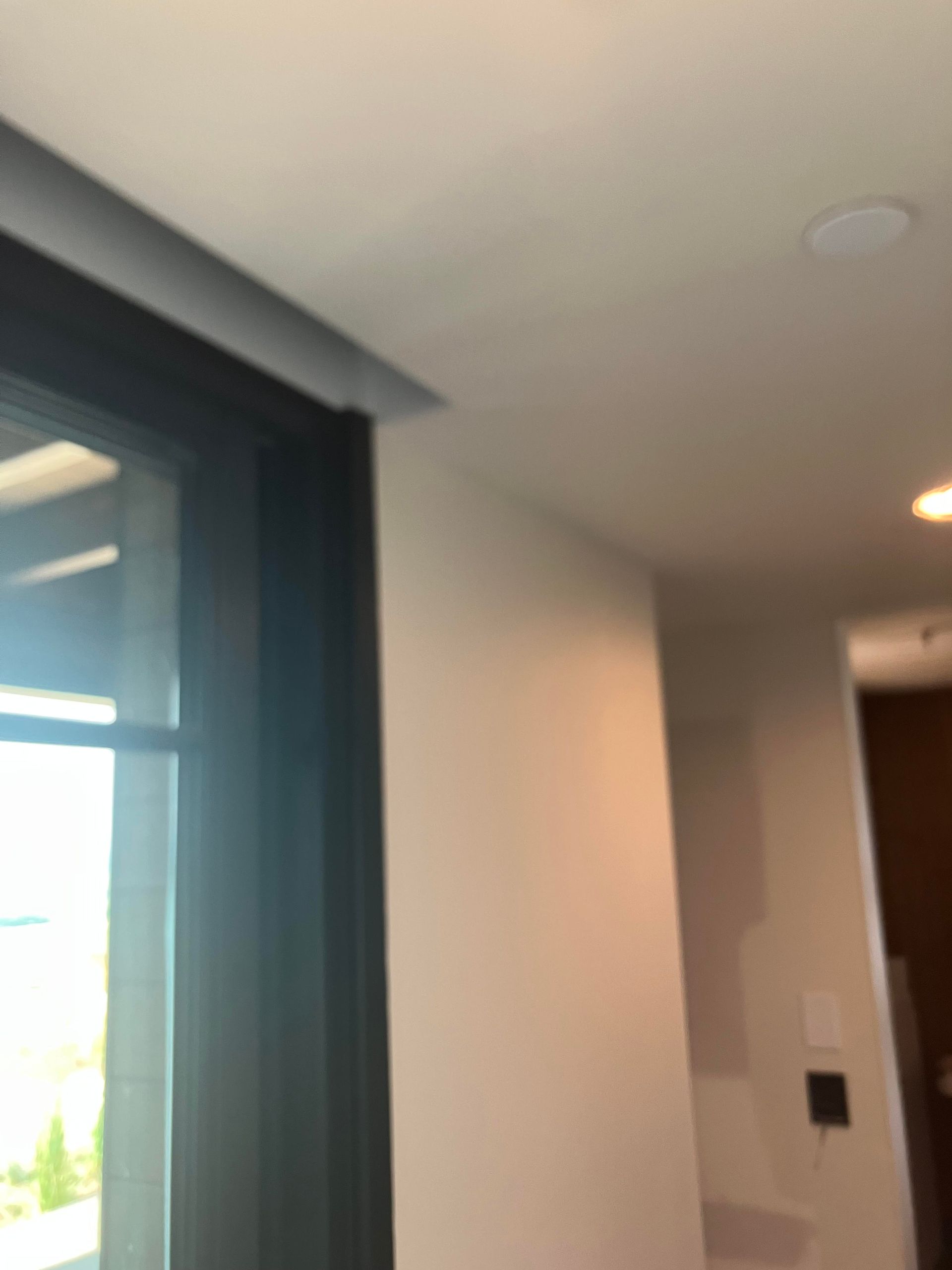 Black framed window next to a light-colored wall and ceiling with a small light fixture.