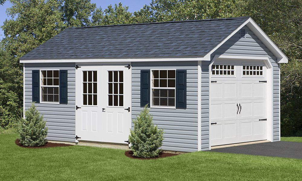 Blue and white shed with a garage door, double doors, and windows, set in a grassy yard.