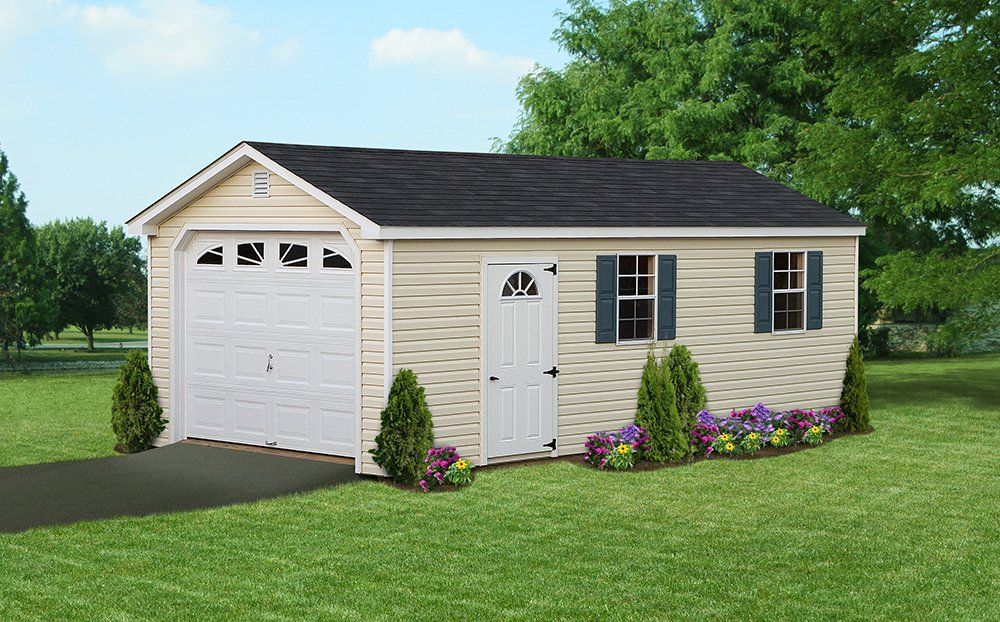 Tan shed with black roof, white garage door and entry door, and blue shutters, on green lawn.