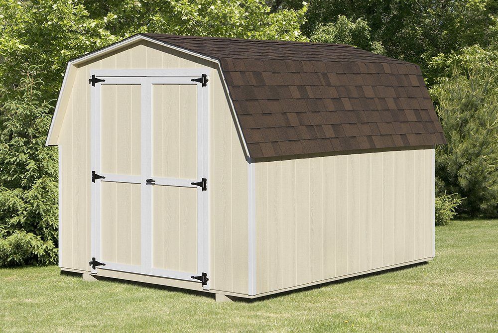 Tan barn-style shed with brown roof on a grassy lawn.
