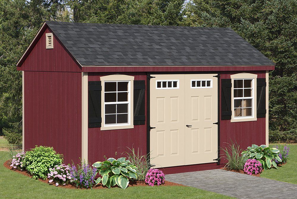 Red garden shed with black roof, tan door, and white-framed windows, set on a lawn with flowers.