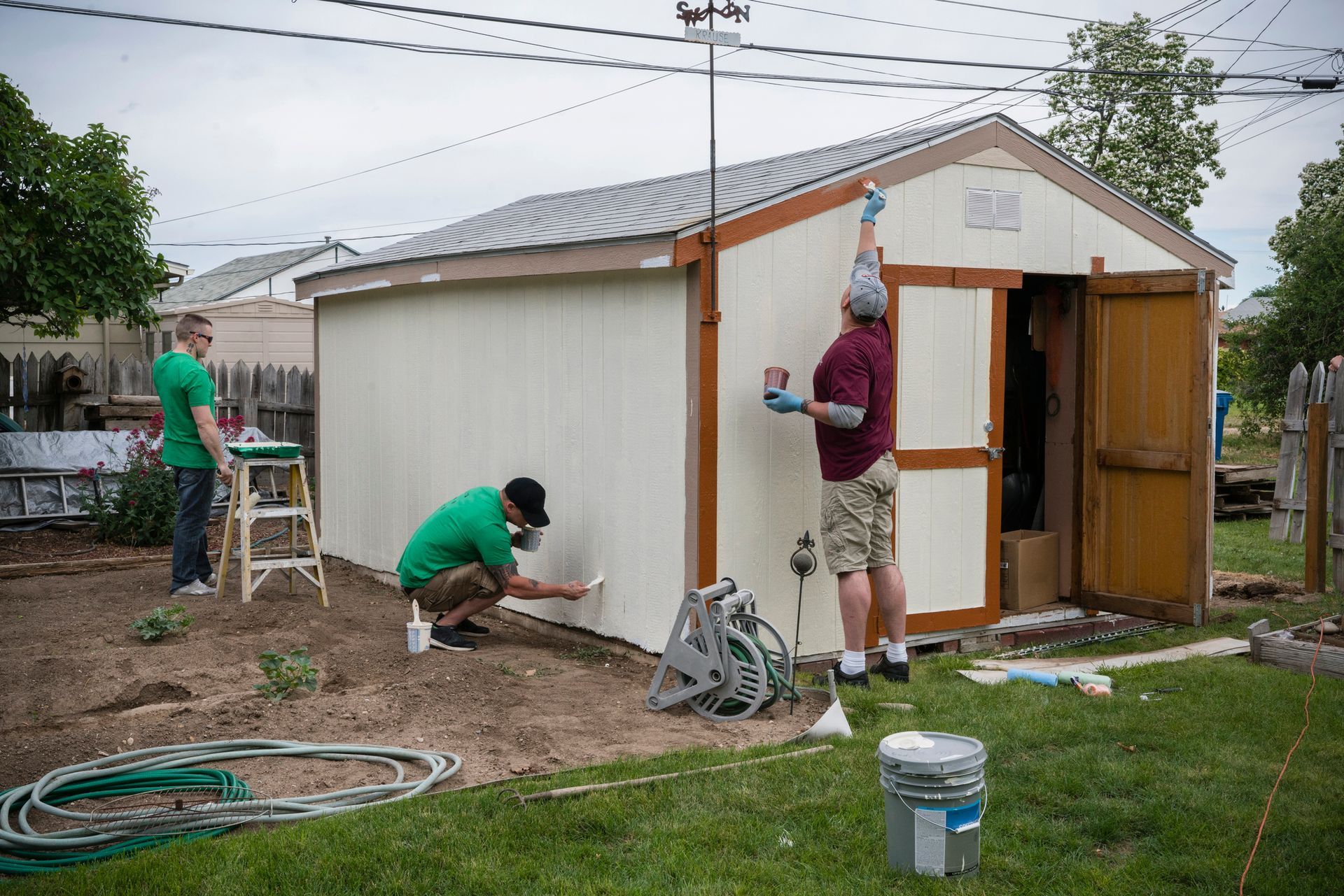Volunteering men painting shed.