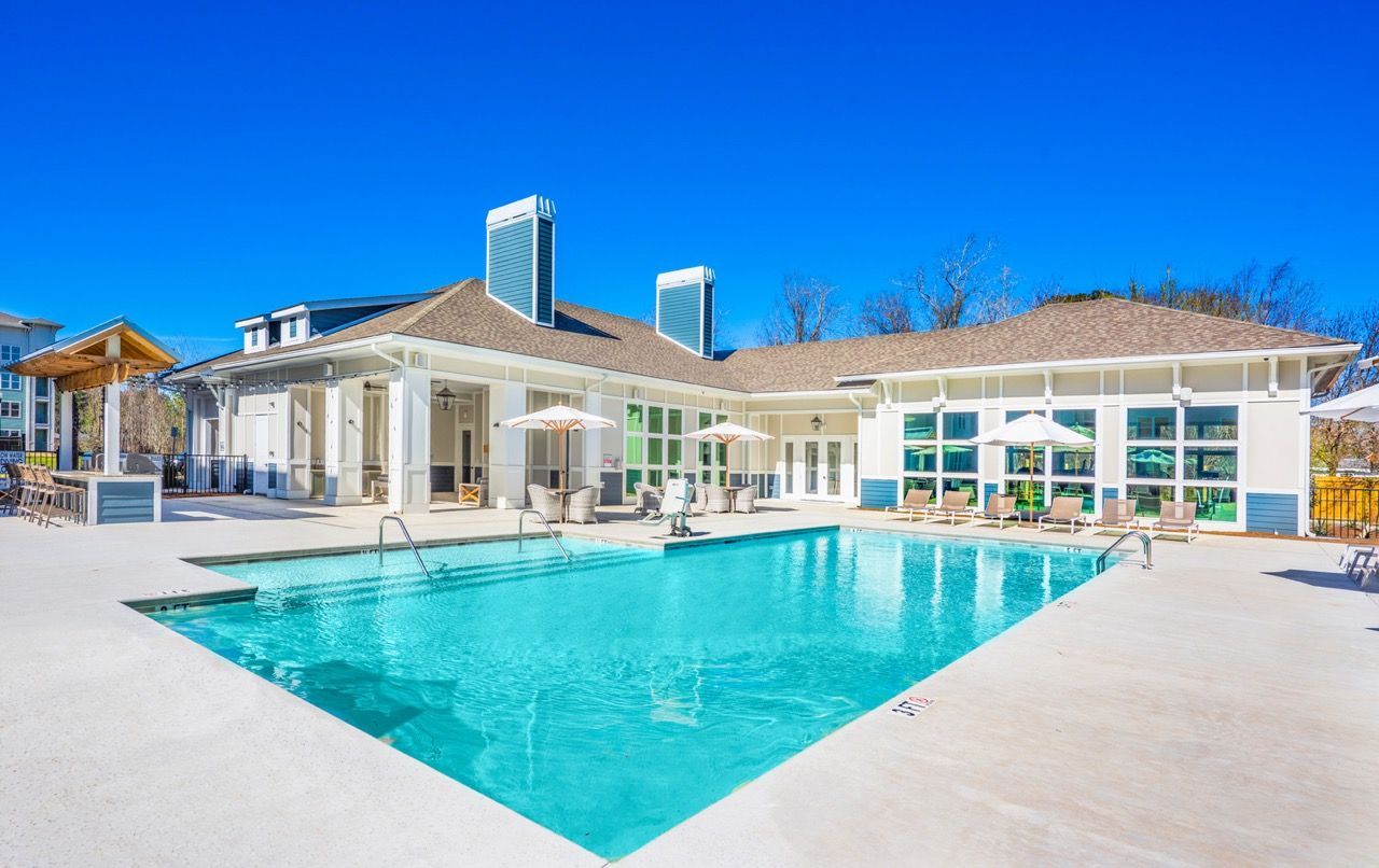 Outdoor swimming pool at an apartment community with lounge chairs and umbrellas.