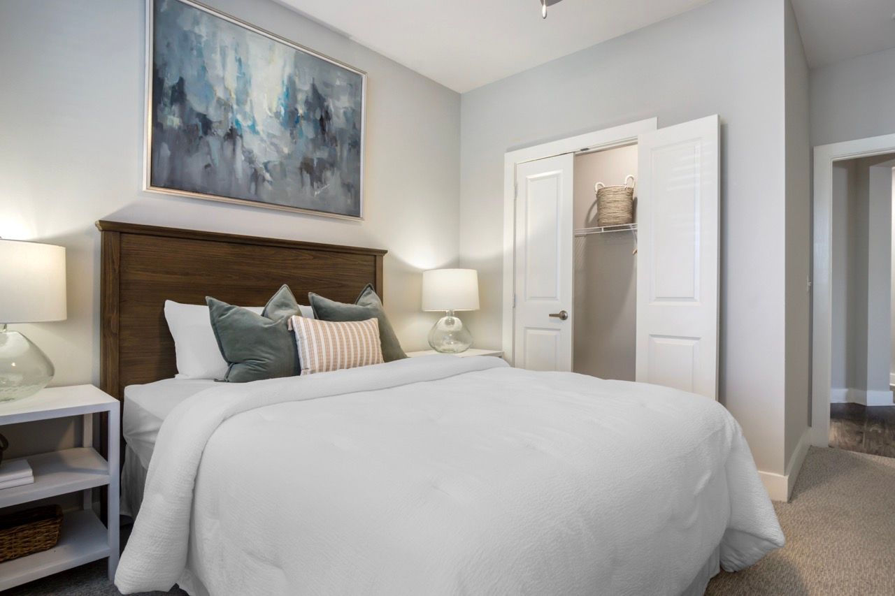 Bedroom in a modern apartment with a large bed, white bedding, and an open closet.