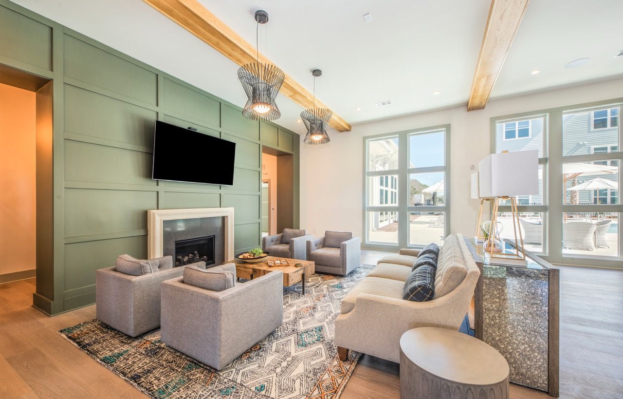 Modern community lounge with green paneled wall, fireplace, and gray seating.