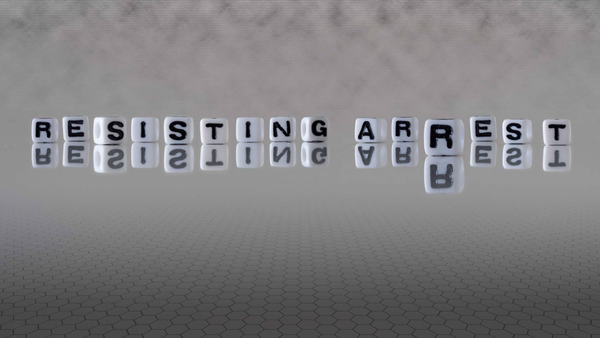 The word “resisting arrest” on white letter cubes on a gray background at JPS Law near Lexington, Ke