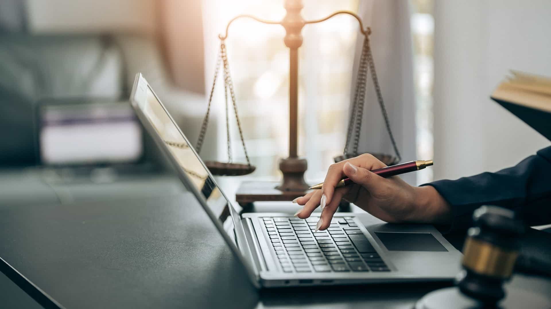 A lawyer typing on a laptop next to pair of judicial scales near Lexington, Kentucky (KY)