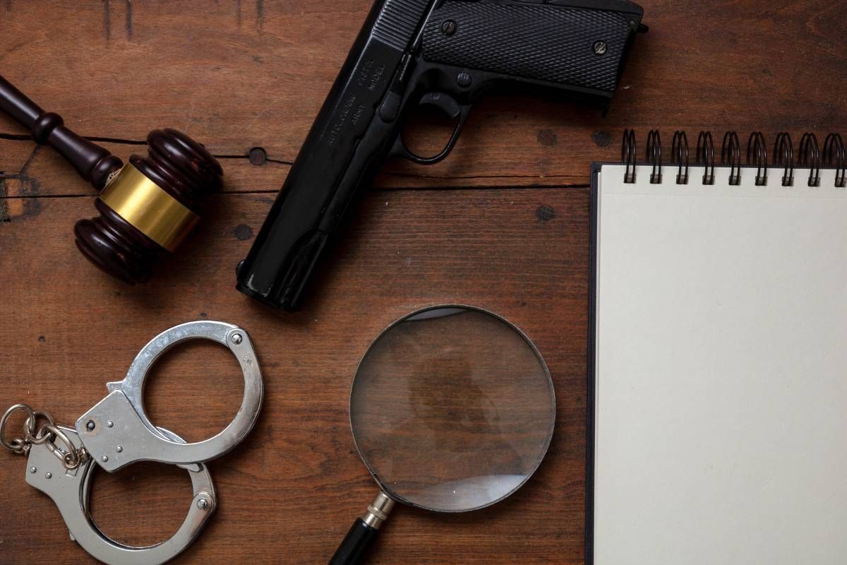 Judge’s gavel, handcuffs, gun, and a blank notepad on wooden background at JPS Law near Lexington, Kentucky (KY)