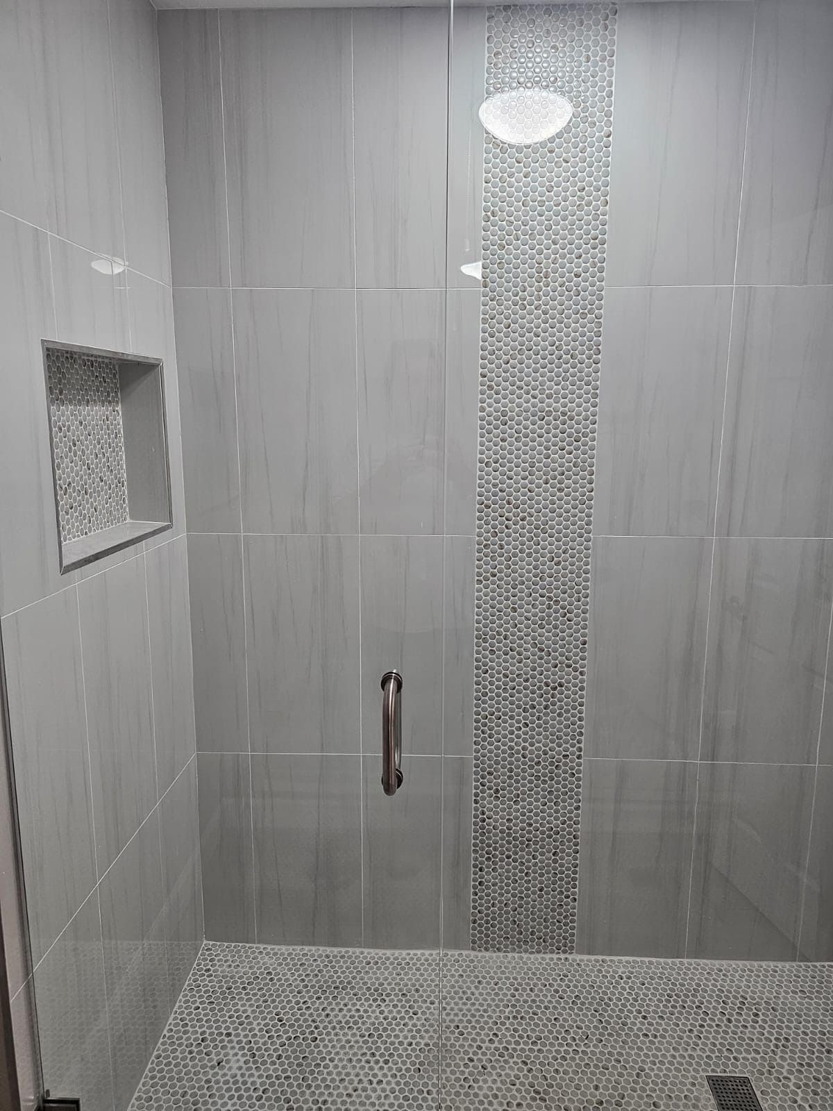 A bathroom with a walk in shower with a glass door.