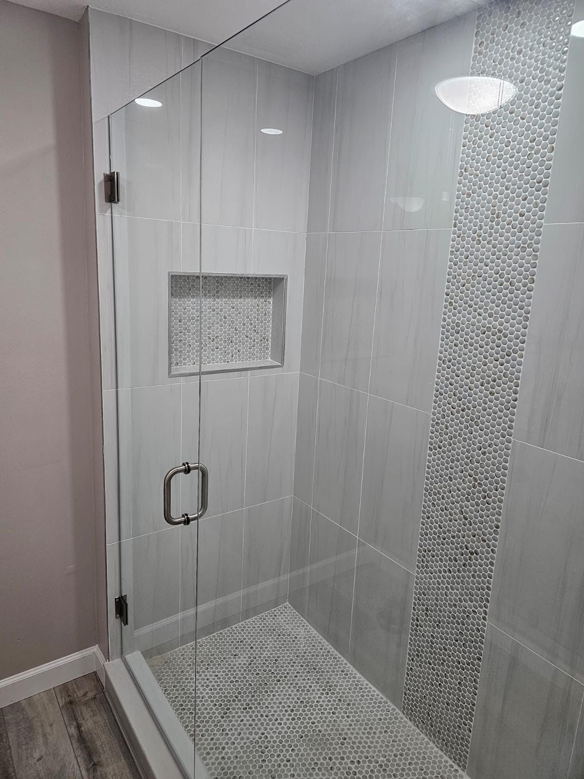A bathroom with a walk in shower with a glass door.