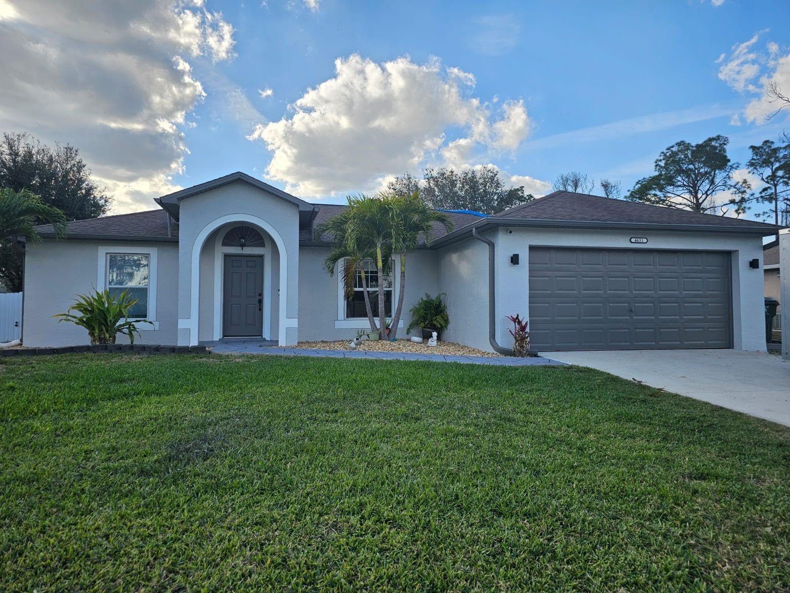A house with a large lawn in front of it and a garage.