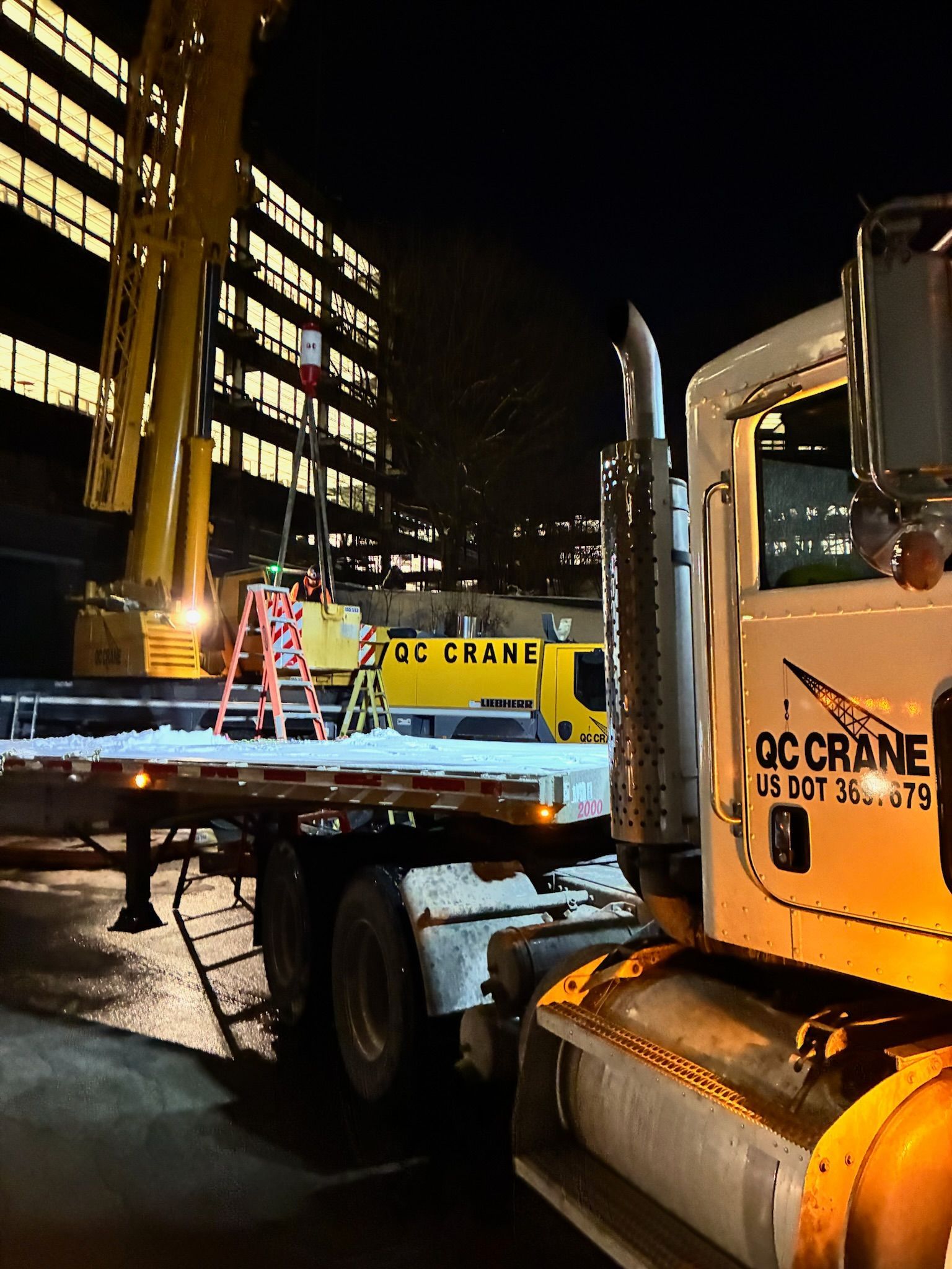 Yellow excavator digging near electrical equipment at a building.