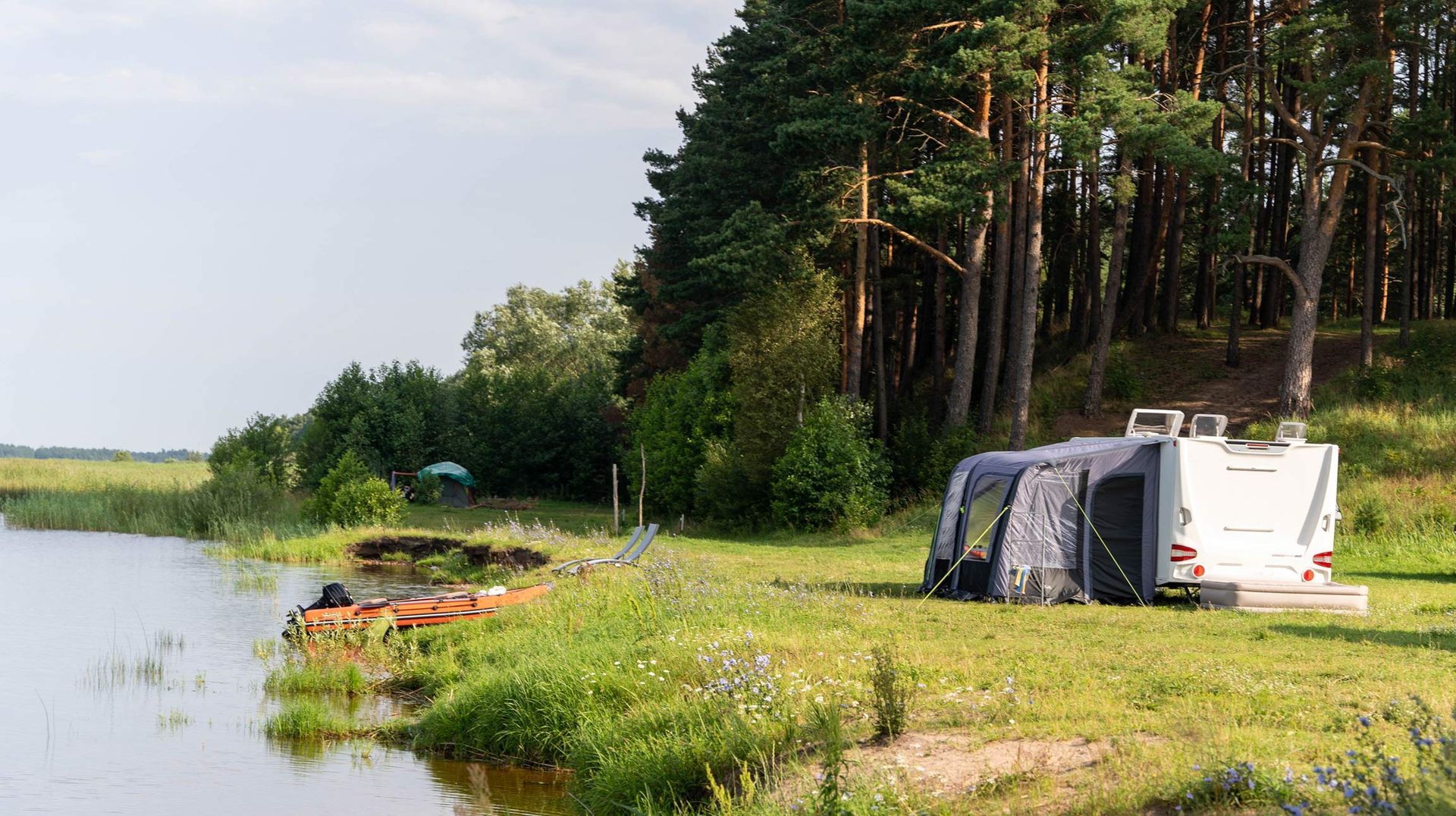 Camper van parked near lake and forest enjoying peaceful camping trip.