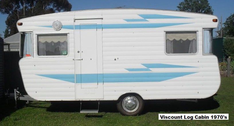 A white caravan with blue stripes is parked in the grass
