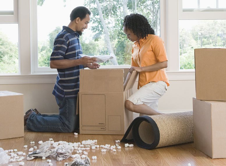 Couple Packing Items Into Cardboard Box