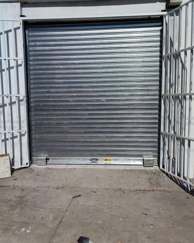 Persiana de seguridad de chapa ondulada cerrada en entorno de hormigón.