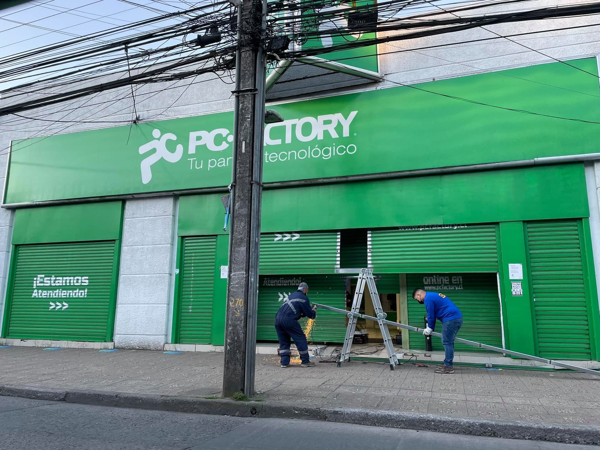 Dos trabajadores instalan un cartel en la tienda verde PC Factory.