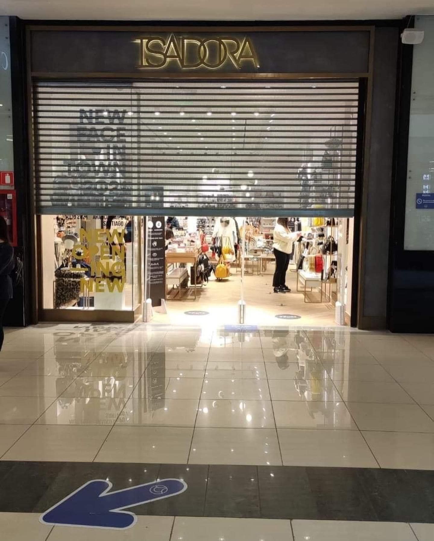 Tienda de cosméticos Isadora con puerta de seguridad parcialmente abierta,