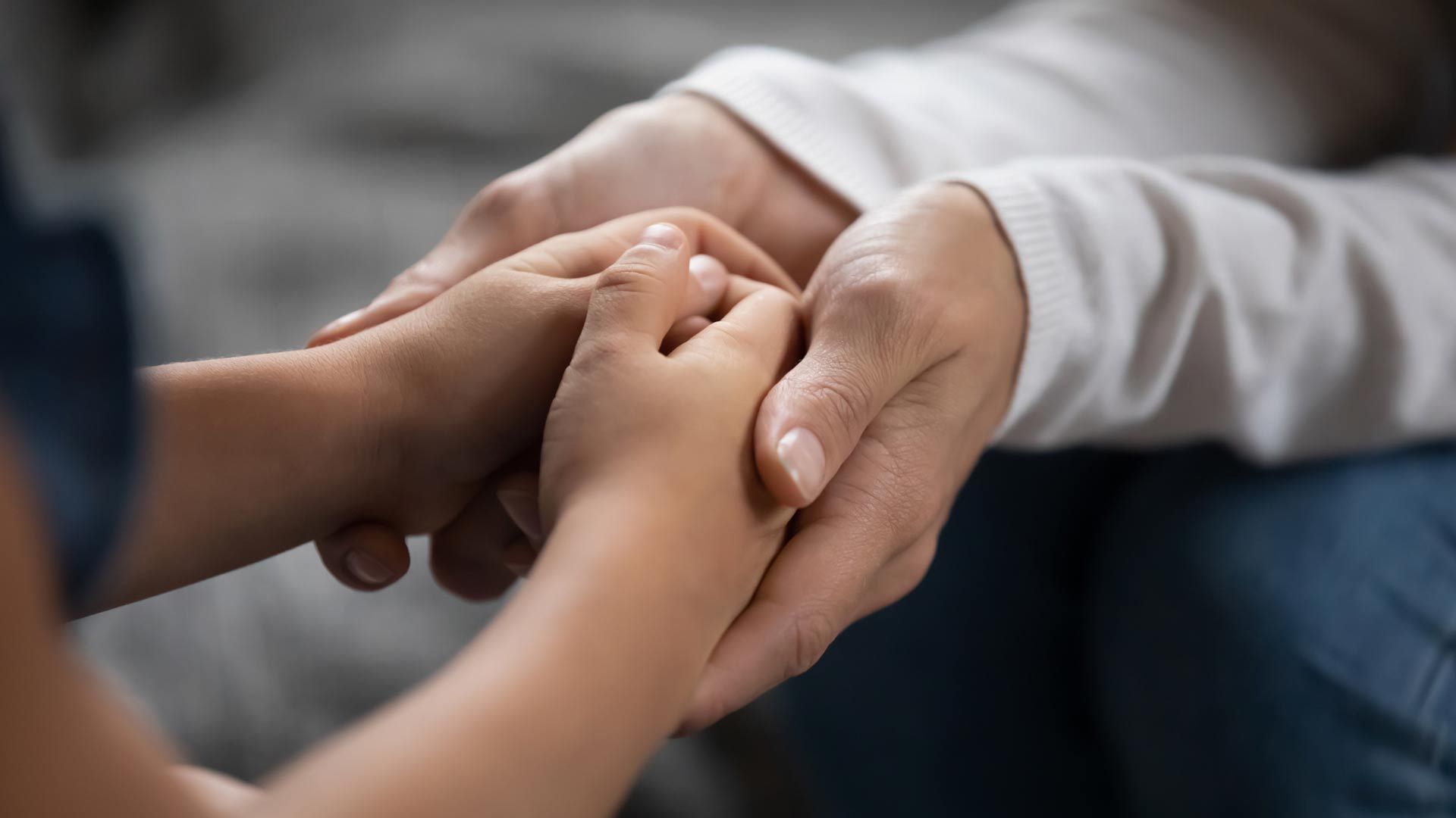 Close up caring mother touching adorable little daughter hands