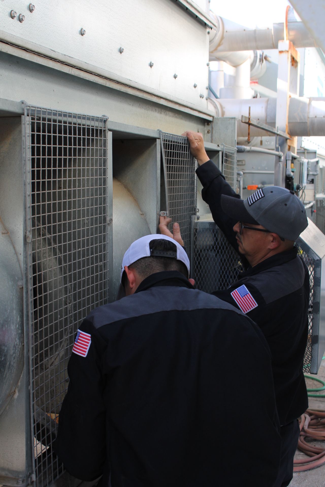 Two men are working on a fan in a factory.