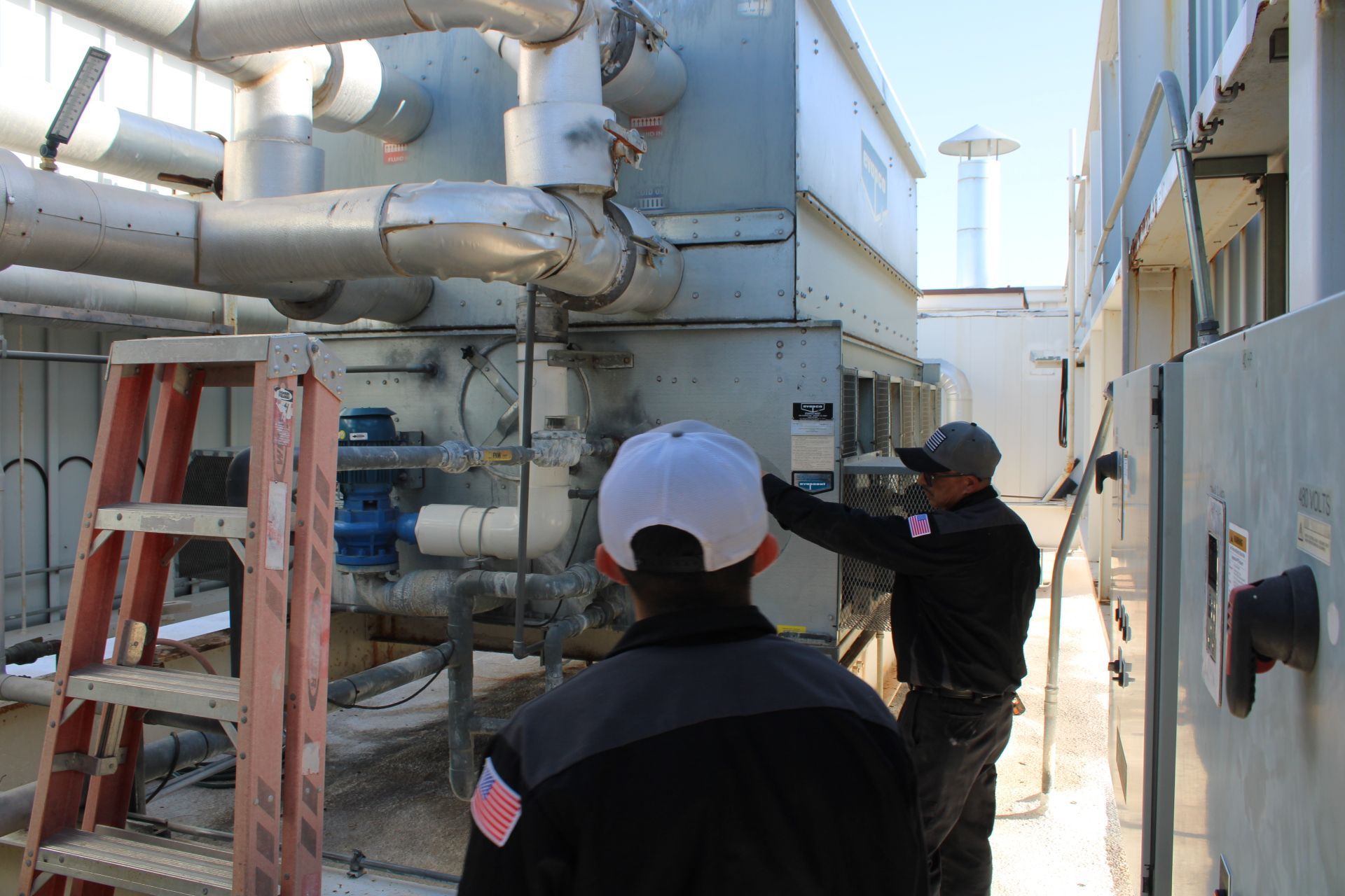 Two men are working on a machine in a factory.