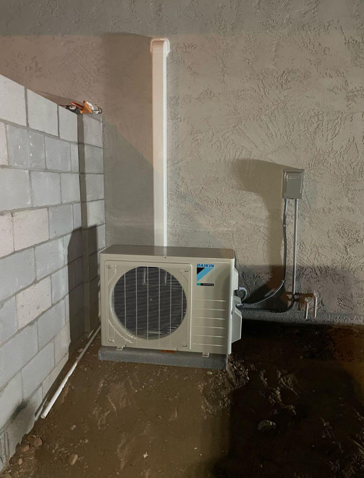 A white air conditioner is sitting in a flooded basement next to a brick wall.