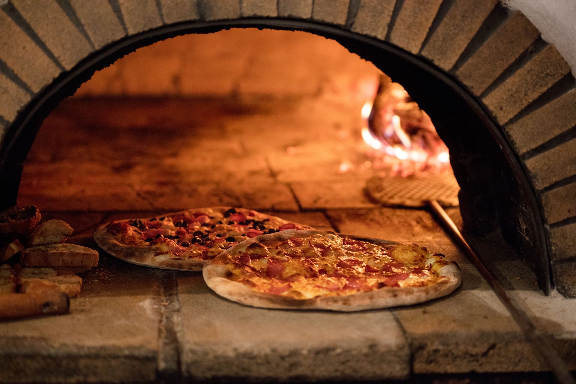 Two pizzas are being cooked in a brick oven