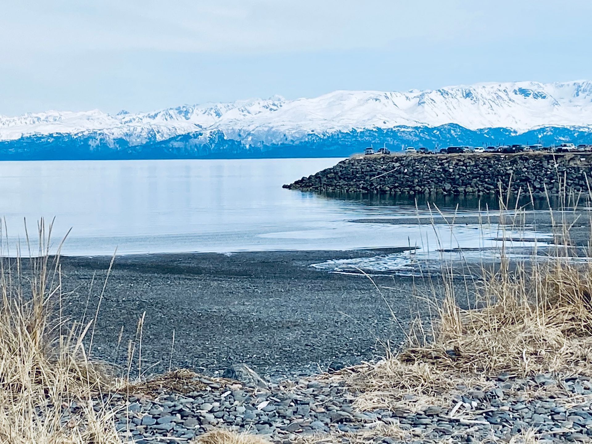 A large body of water with mountains in the background and a rocky shoreline.