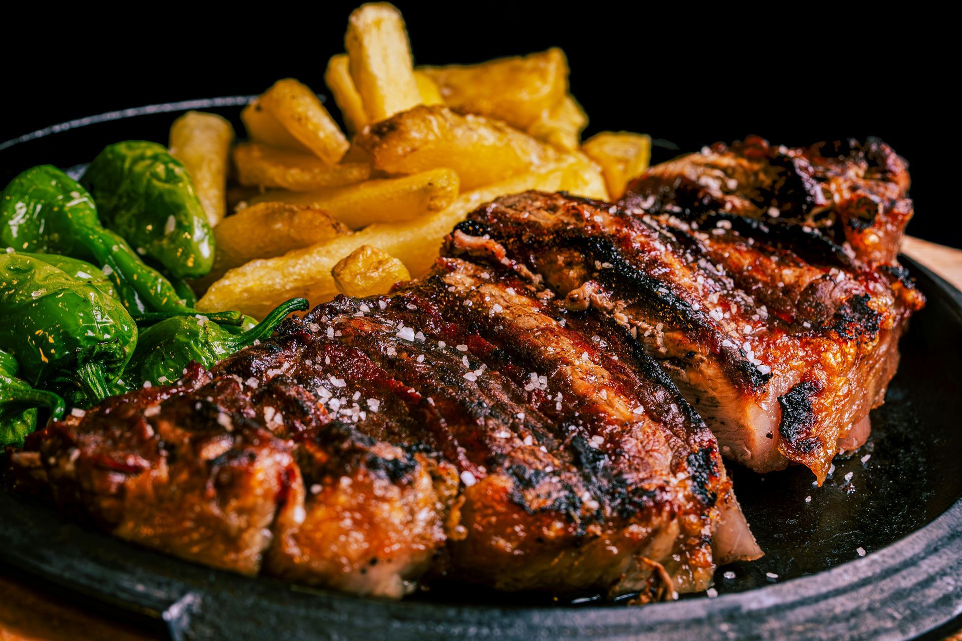 A close up of a steak and french fries on a plate.