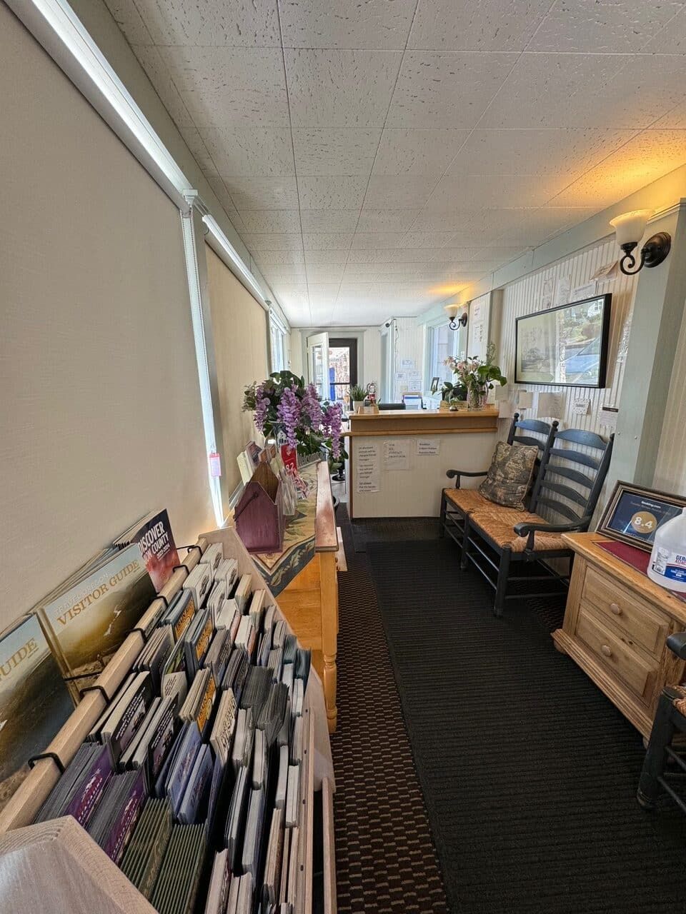 A long hallway with rocking chairs and a shelf full of books.