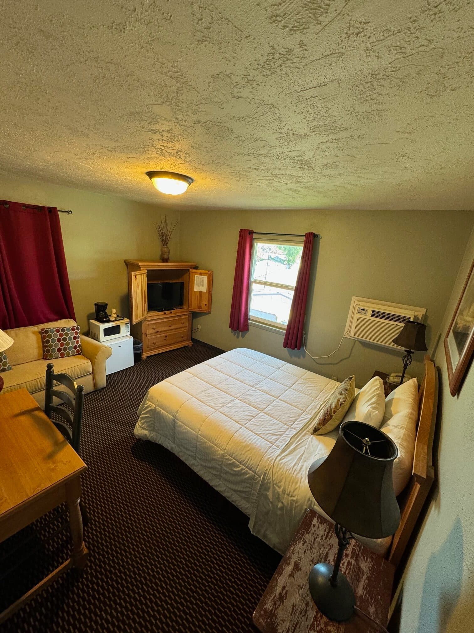 A hotel room with a king size bed , a couch , a desk , and a television.