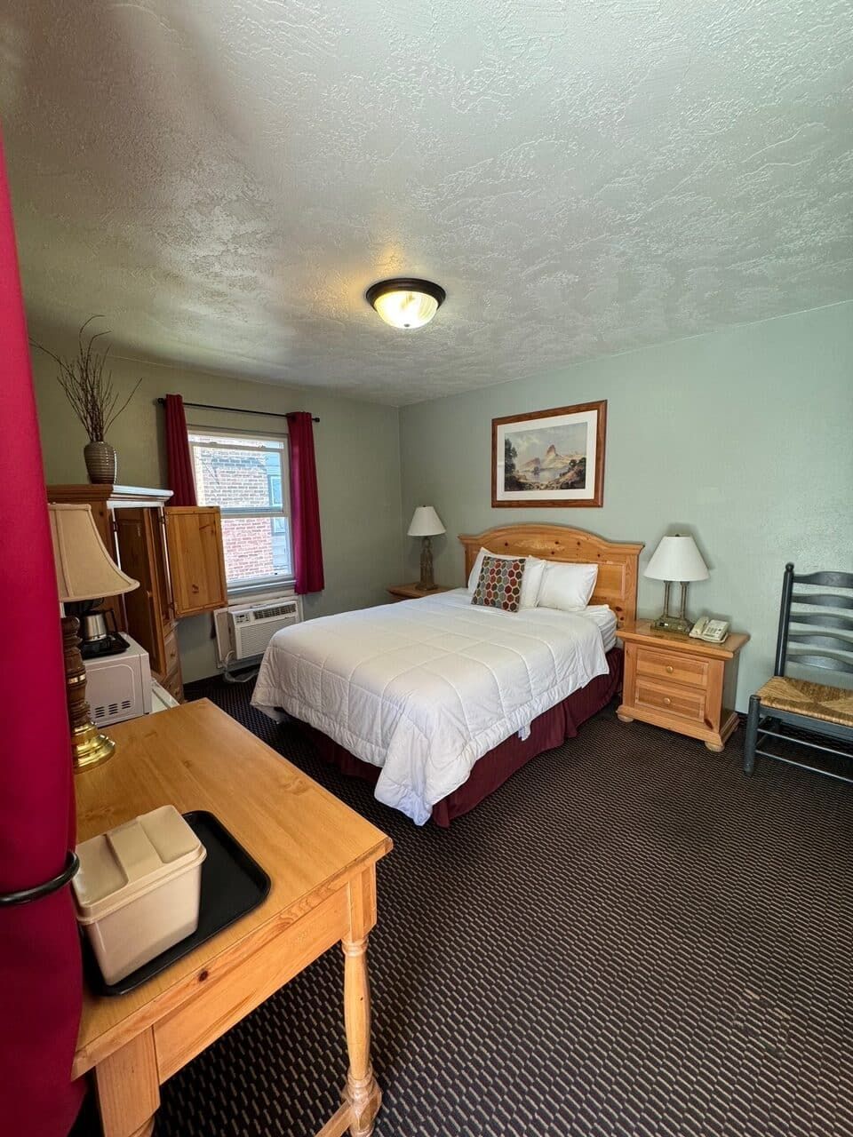 A hotel room with a king size bed and a desk