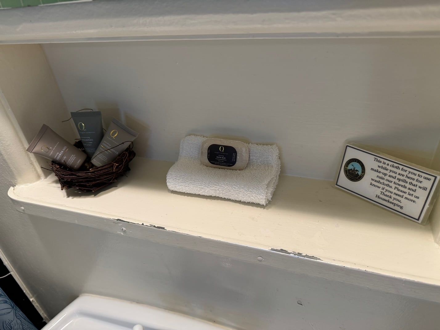 A bathroom shelf with a towel , soap and lotion on it.
