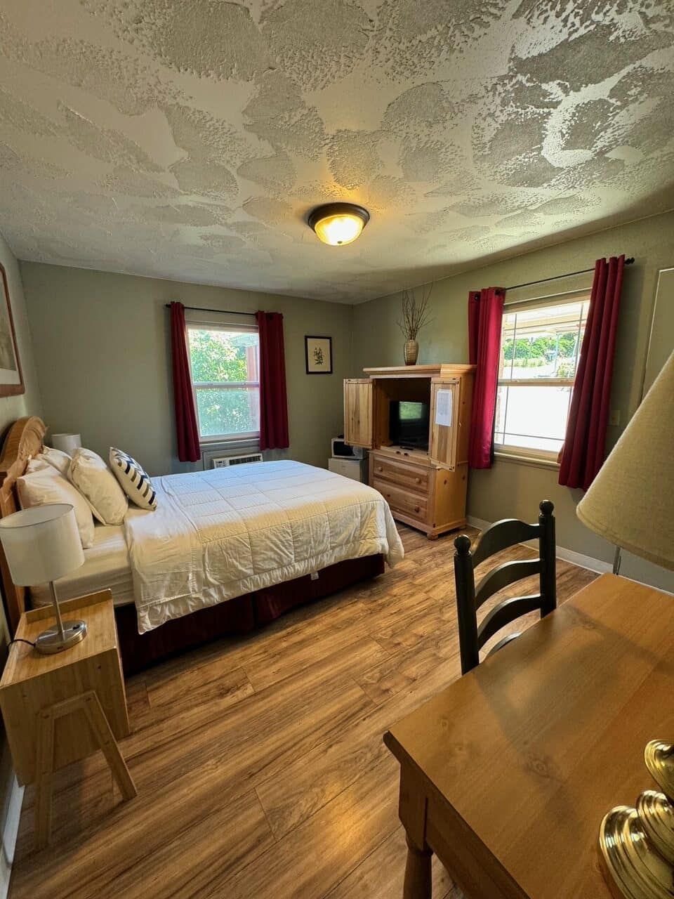 A bedroom with a bed , desk , chair , lamp and television.