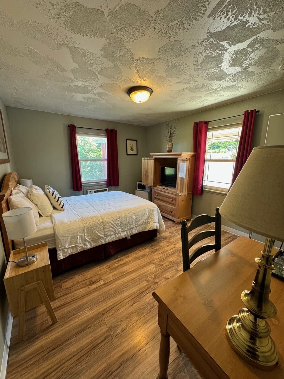 A bedroom with a bed , desk , lamp and television.