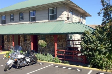 A motorcycle is parked in front of a building with a green roof