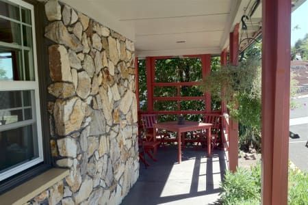 A porch with a table and chairs and a stone wall
