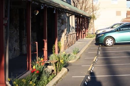 A green car is parked in a parking lot in front of a building.