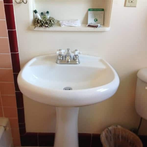 A bathroom with a pedestal sink and toilet