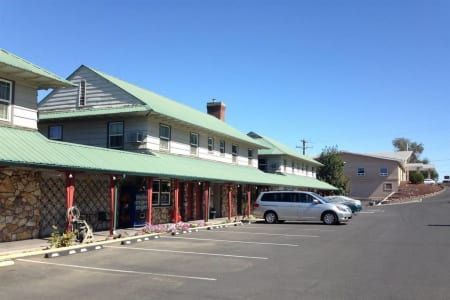 A white van is parked in front of a building with a green roof.