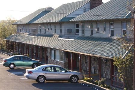 Two cars are parked in front of a building with a green roof