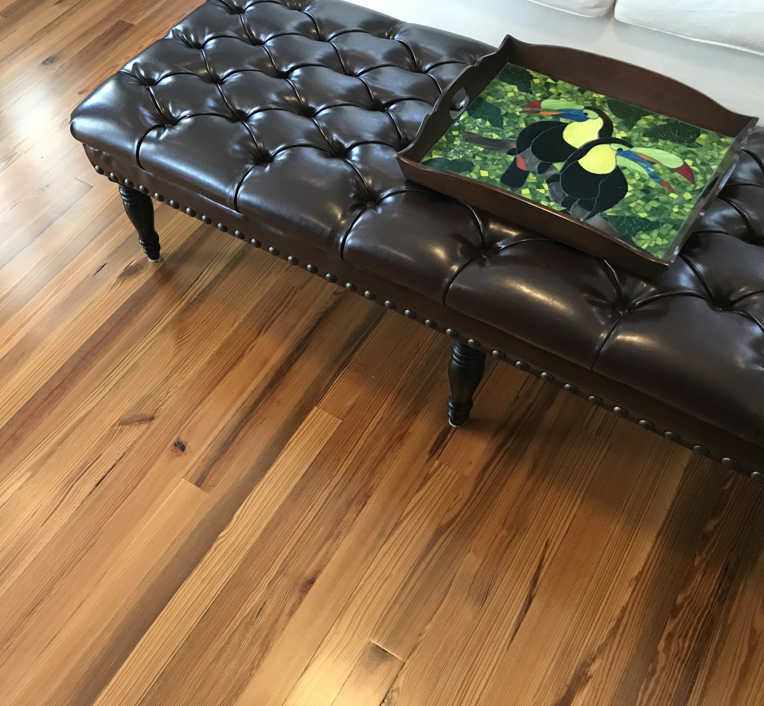 hardwood floor with leather ottoman and breakfast tray inlayed with toucan tile mosaic