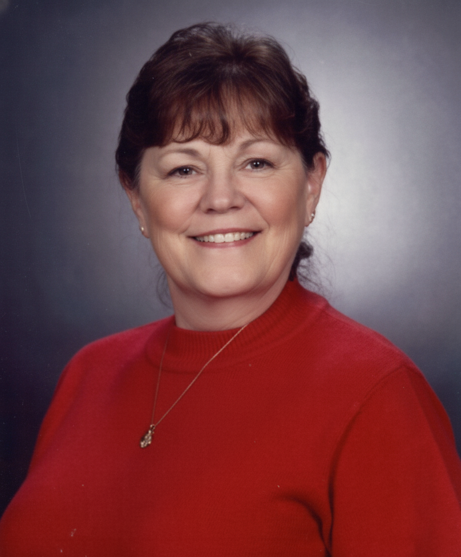 Woman with brown hair and bangs, smiling, wearing a red sweater, against a gray background.