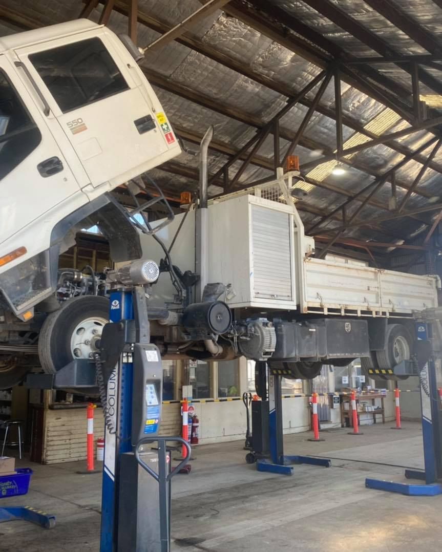 A White Truck is Sitting on a Lift in a Garage — BDM Heavy Vehicle Repairs In Port Macquarie, NSW